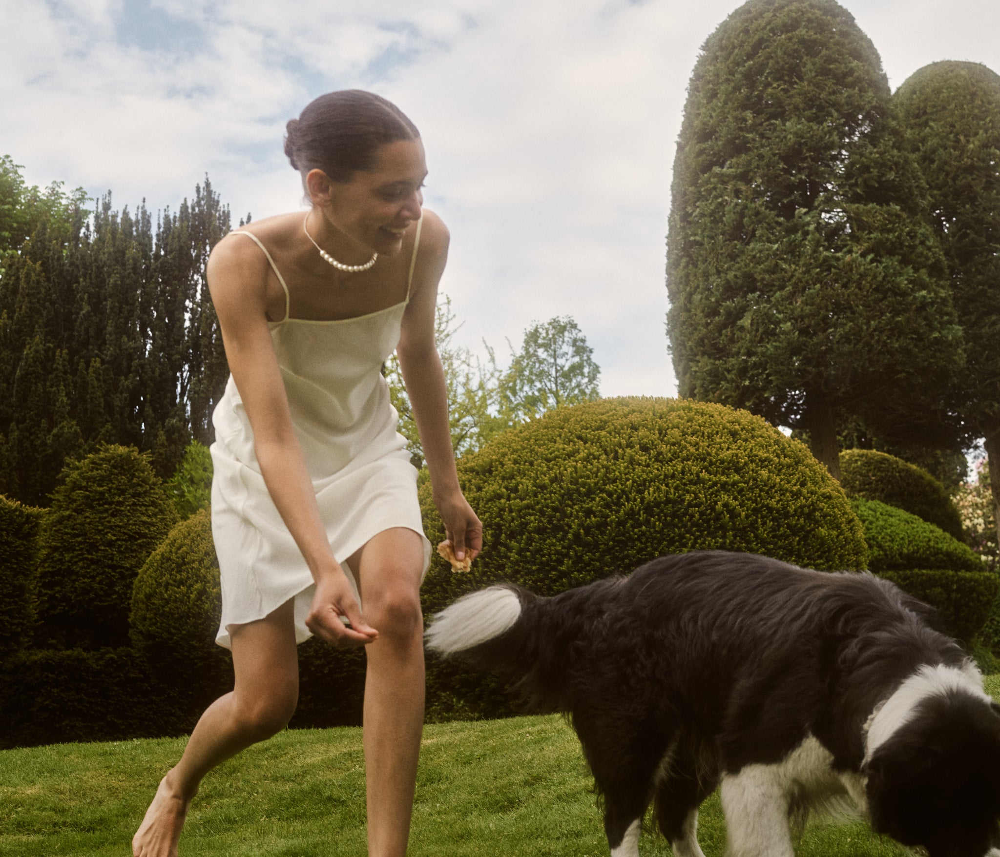 Photography of a woman wearing Peggy pearl necklace while playing with Sophie's dog Snoopy