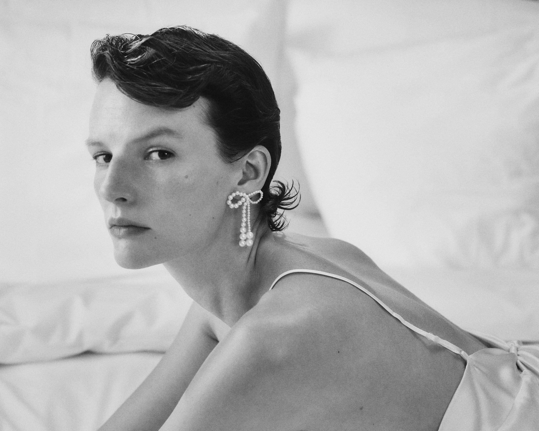 Model wearing bow-shaped Grande Rosette de Perle earrings.