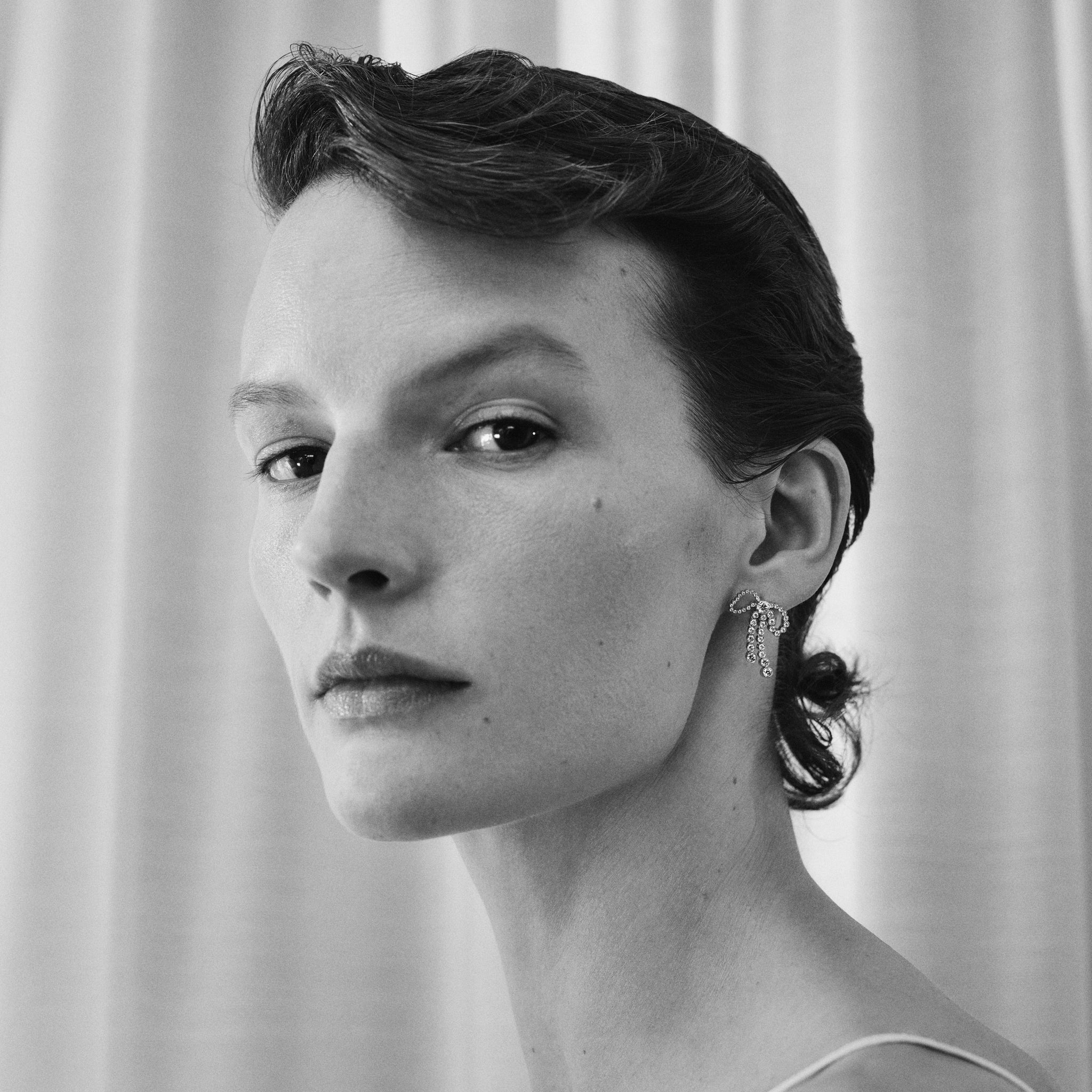 Model wearing Rosette Diamant bow shaped diamond earring.