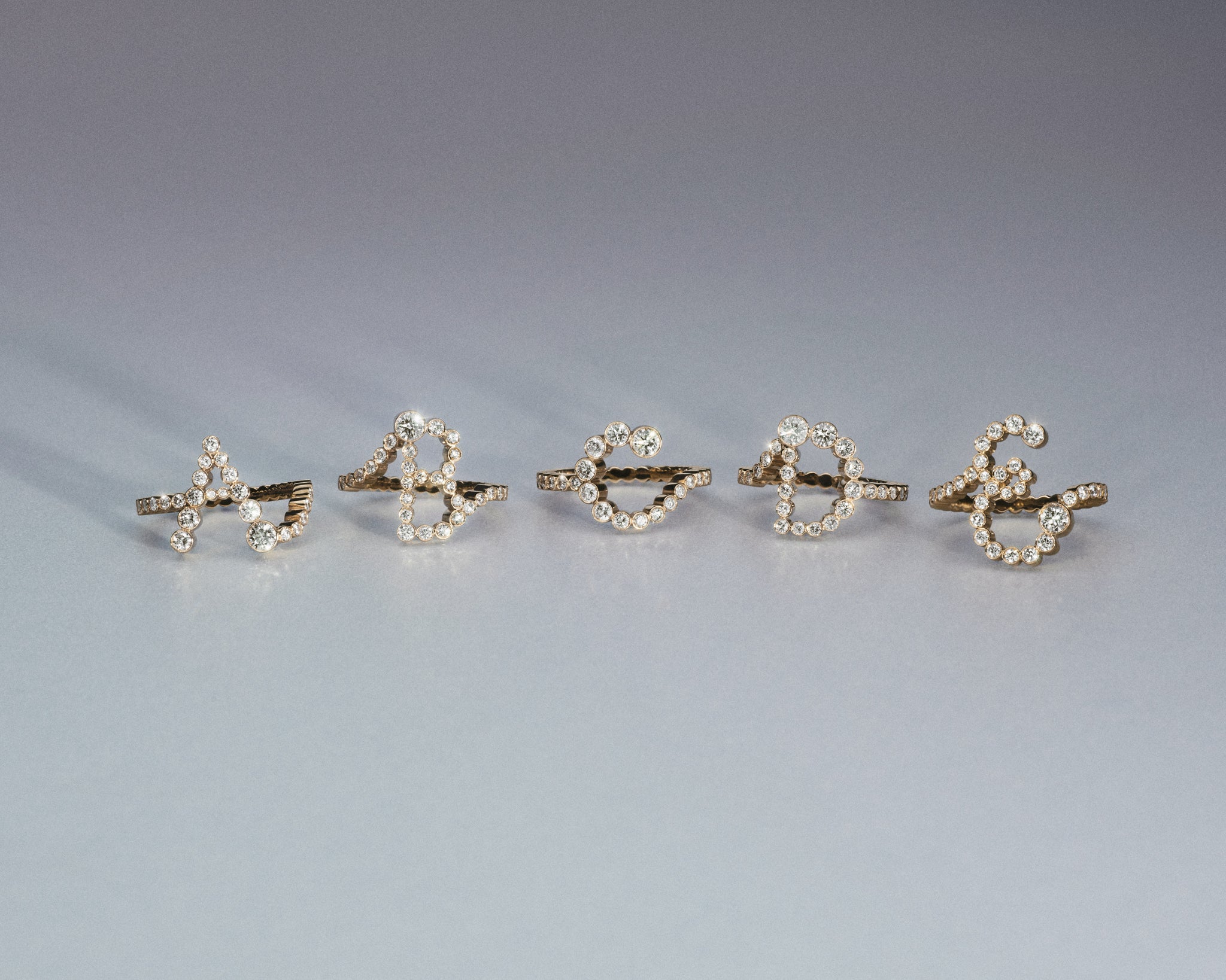 Letter diamond rings in yellow gold.