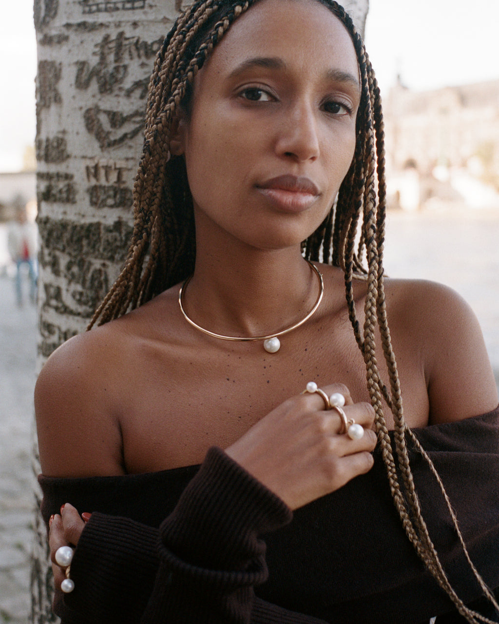 Model wearing the La Beauté yellow gold choker with a large round freshwater pearl in the center, alongside three yellow gold rings with large freshwater pearls.