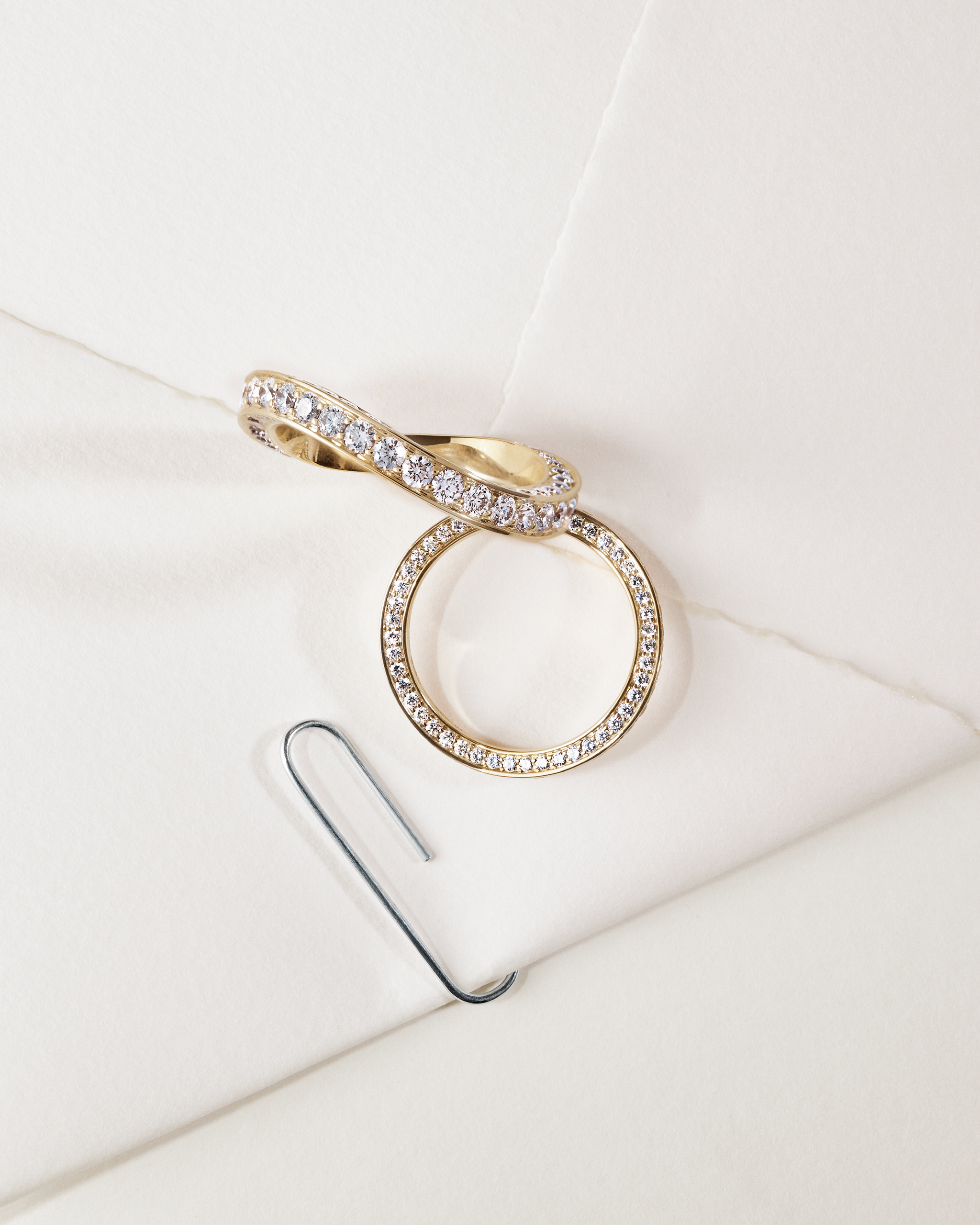 Grande Nous Sommes wedding band for him with Nous Sommes wedding band for her, both placed on an envelope