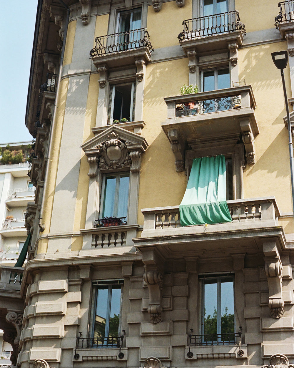 Decorative building facade with ornate balconies and a green curtain in Italy.