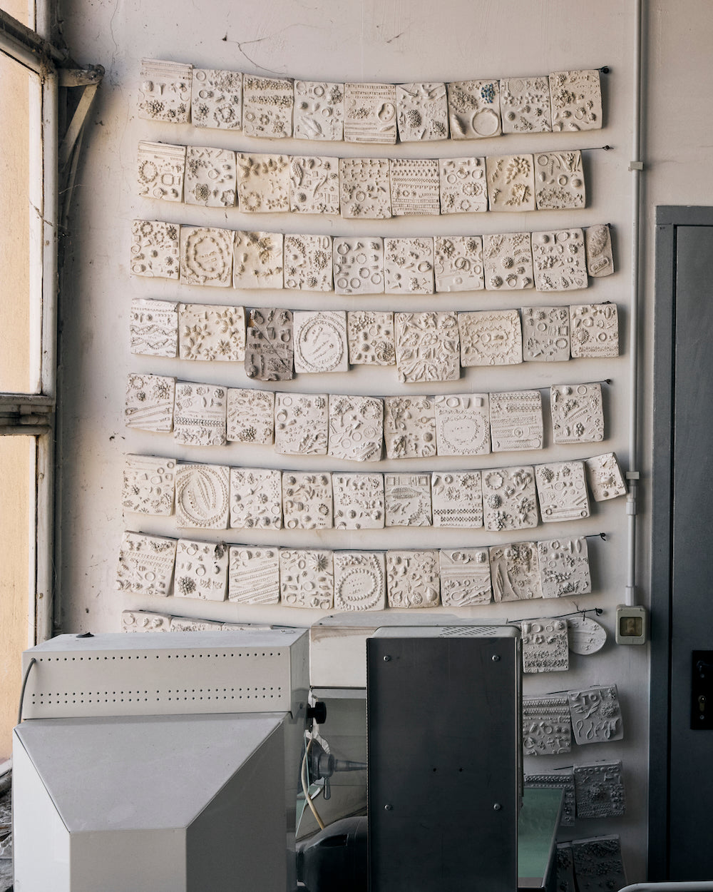 Collection of jewellery molds on a wall in a workshop setting.