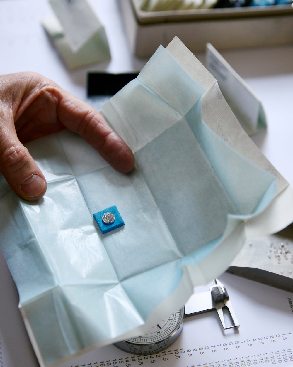 Hand holding wrapping with one loose diamond on a light background