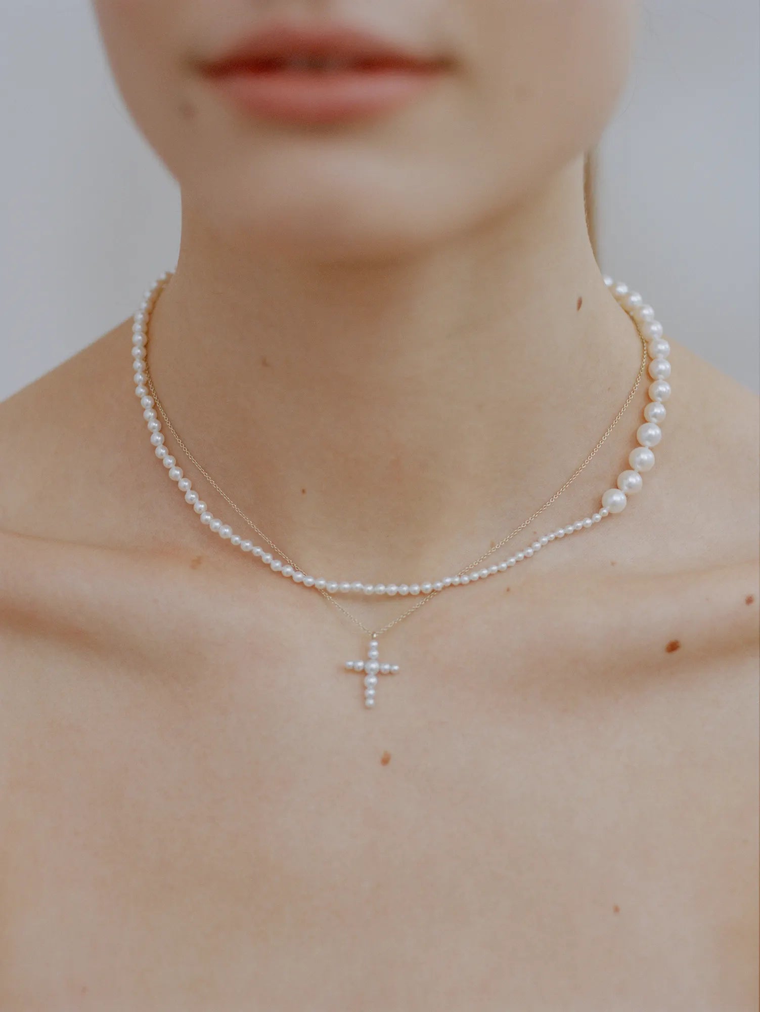 Model wearing two pearl necklaces, Peggy Deux and Petite Fellini Croix