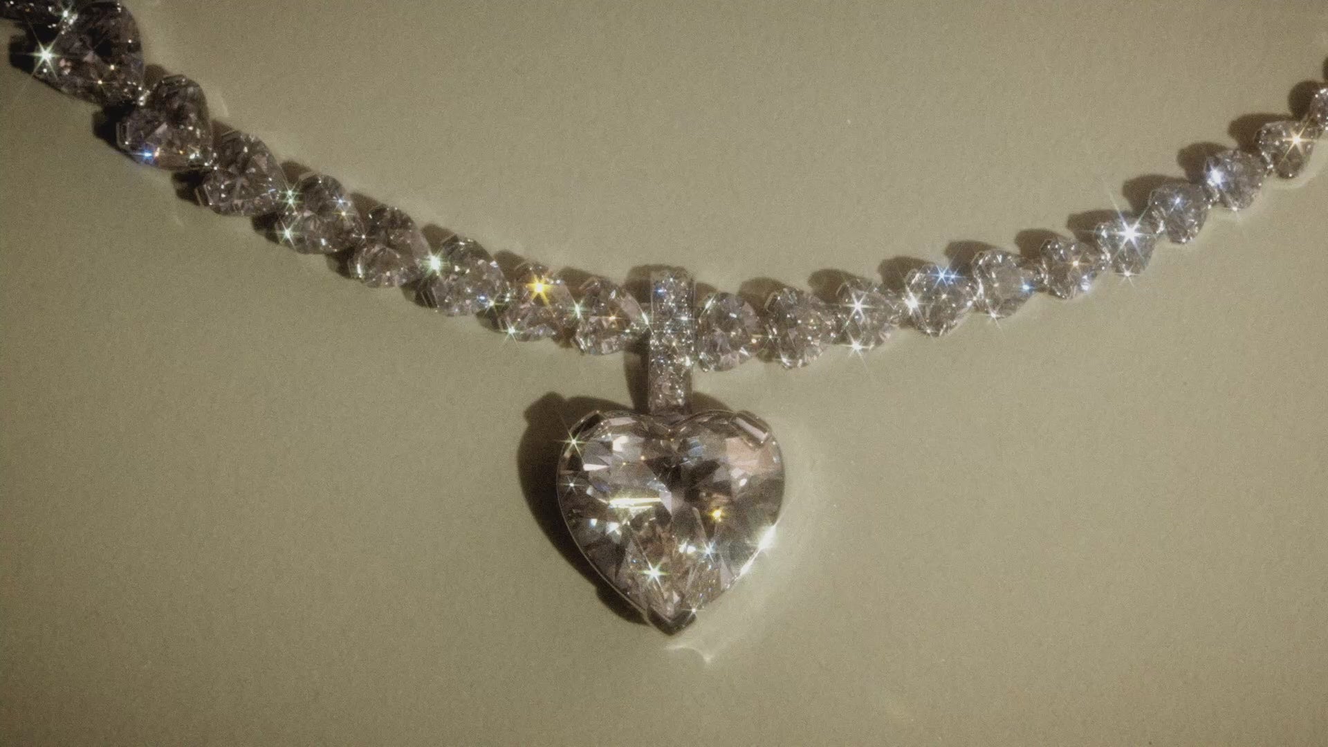 Load video: Sky 4 diamond necklace with heart shaped diamonds with pendant on a beige background
