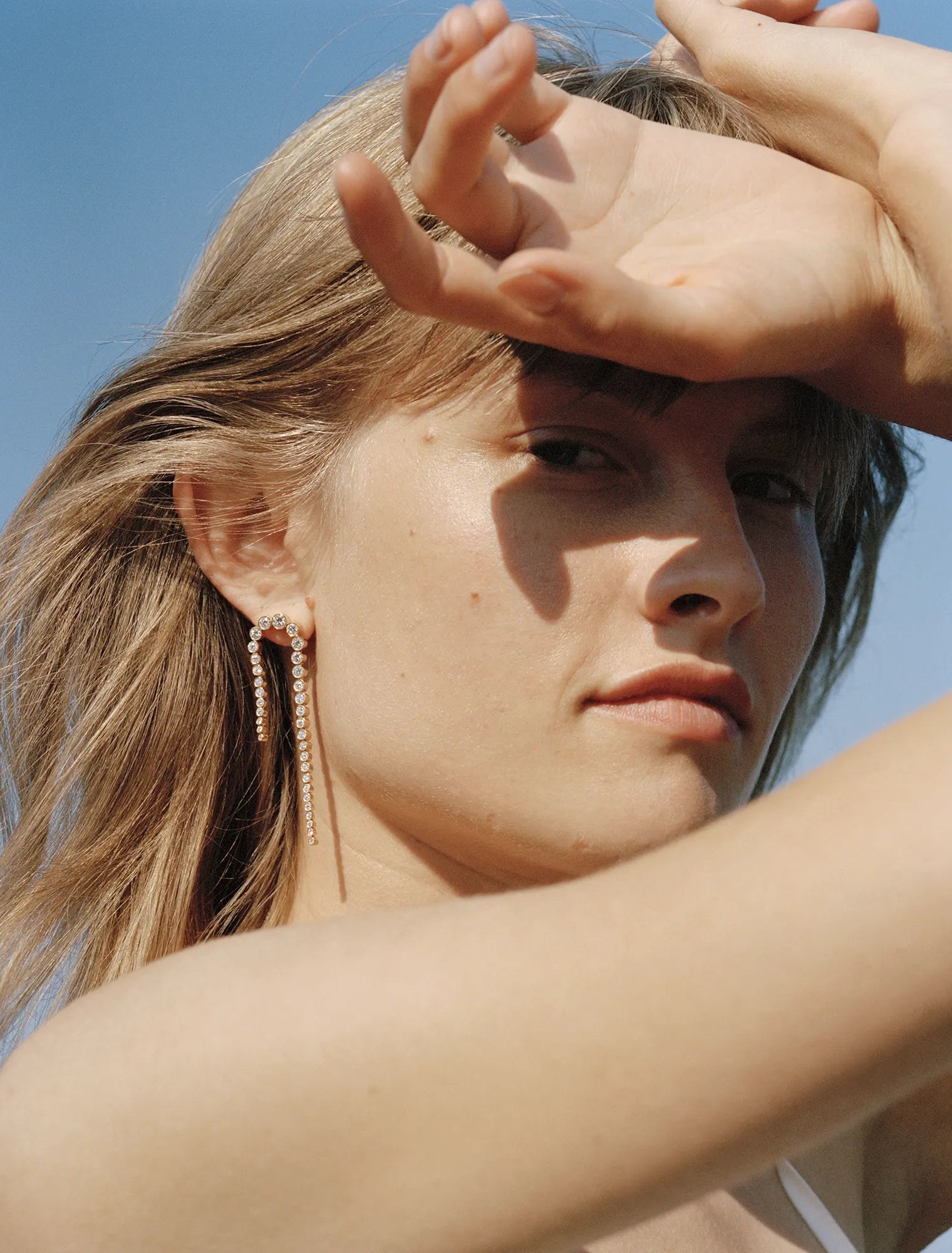 Model wearing Sandro Nuit earring, photographed in front of blue sky